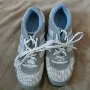 White, gray and baby blue Champion tennis shoes.